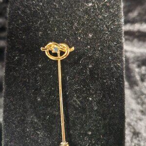 Small pretzel shaped gold tone pin with blue stone
